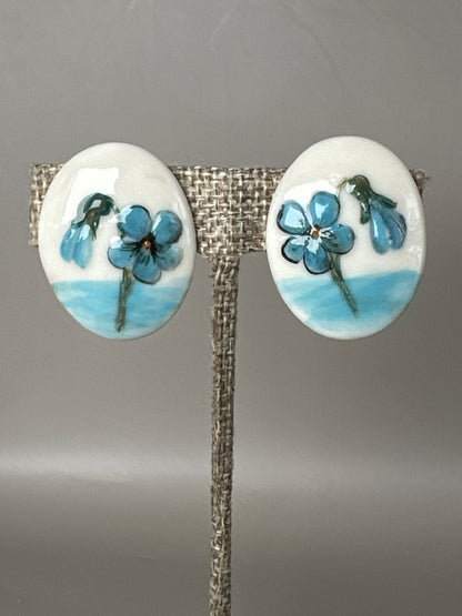 Mid-Century hand-painted ceramic screwback earrings with blue floral decoration, front view on display stand