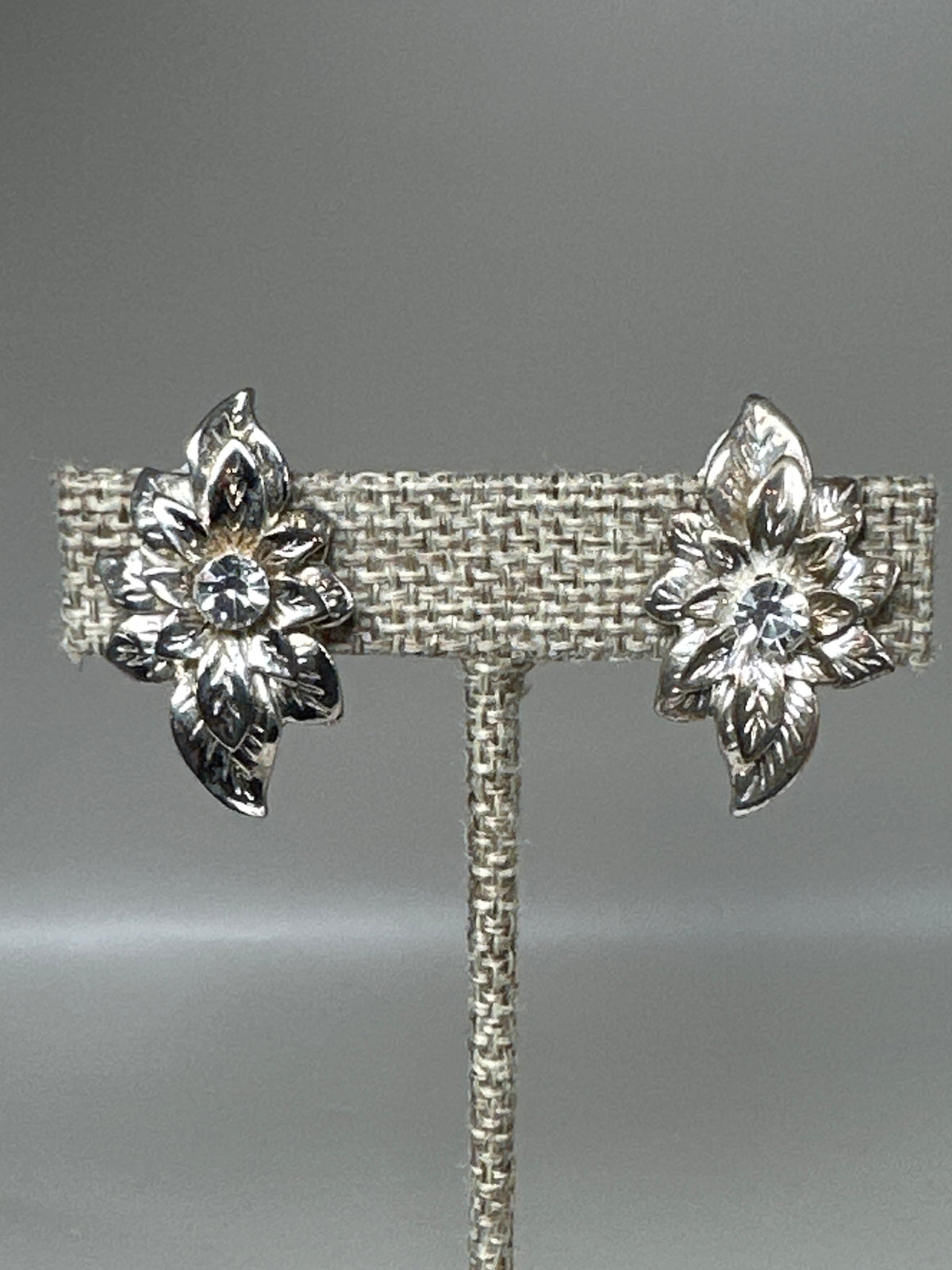 Close-up front view of rhinestone-centered leaf spray earrings highlighting prong-set stones