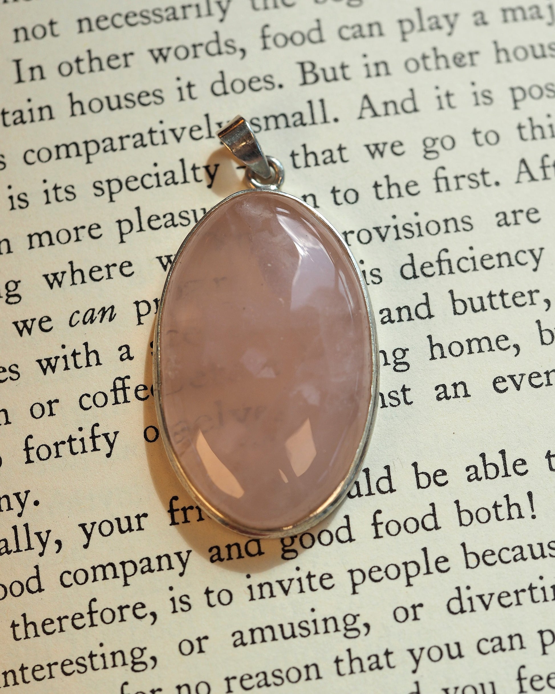 sterling silver rose quartz pendant with oval cabochon in bezel setting, front view on book page