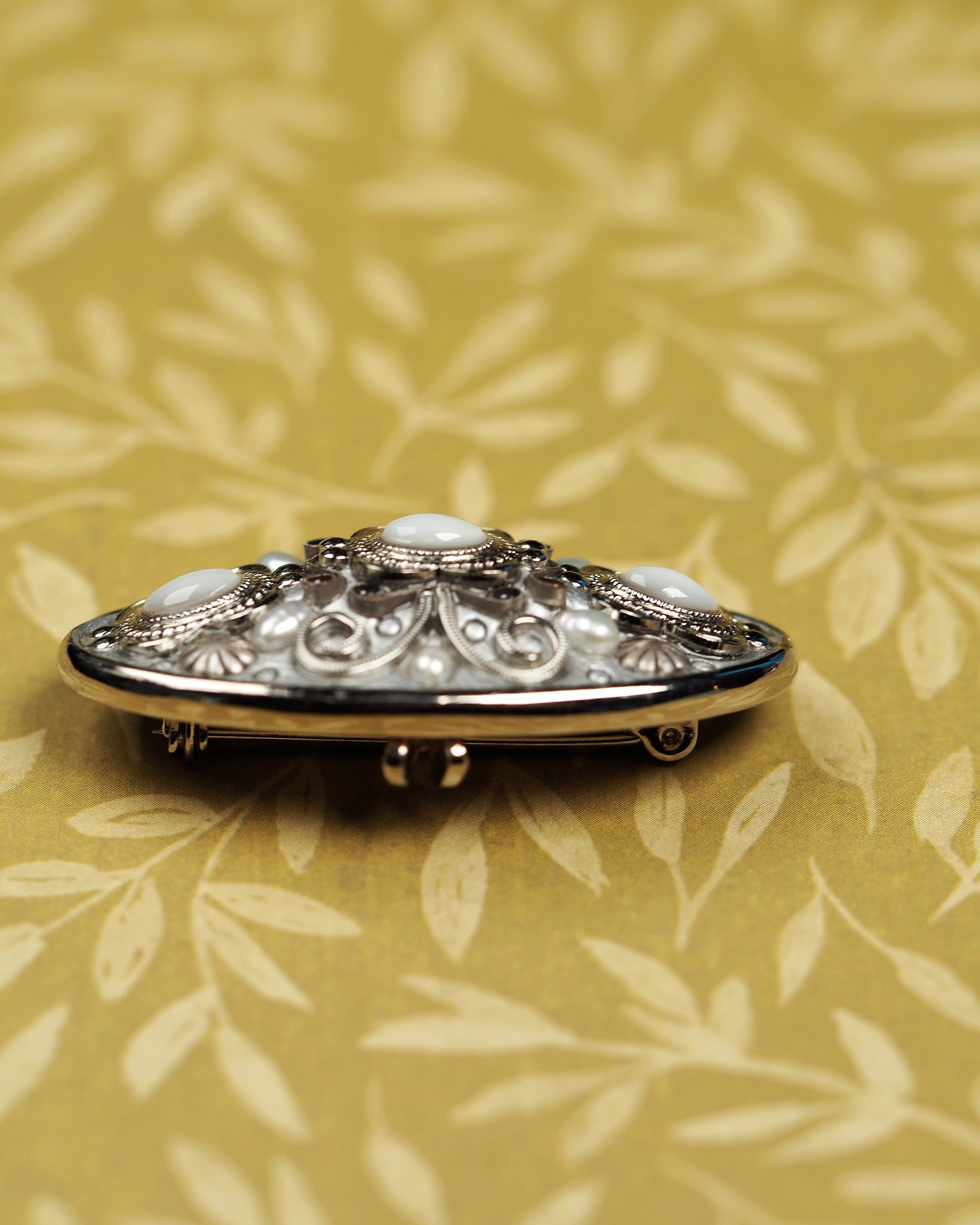 Side profile of Michal Golan oval brooch showing openwork construction and pin clasp