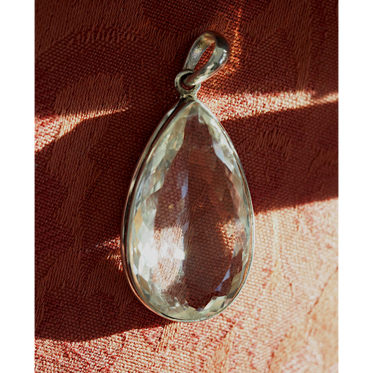 Large faceted clear teardrop pendant in warm sunlight