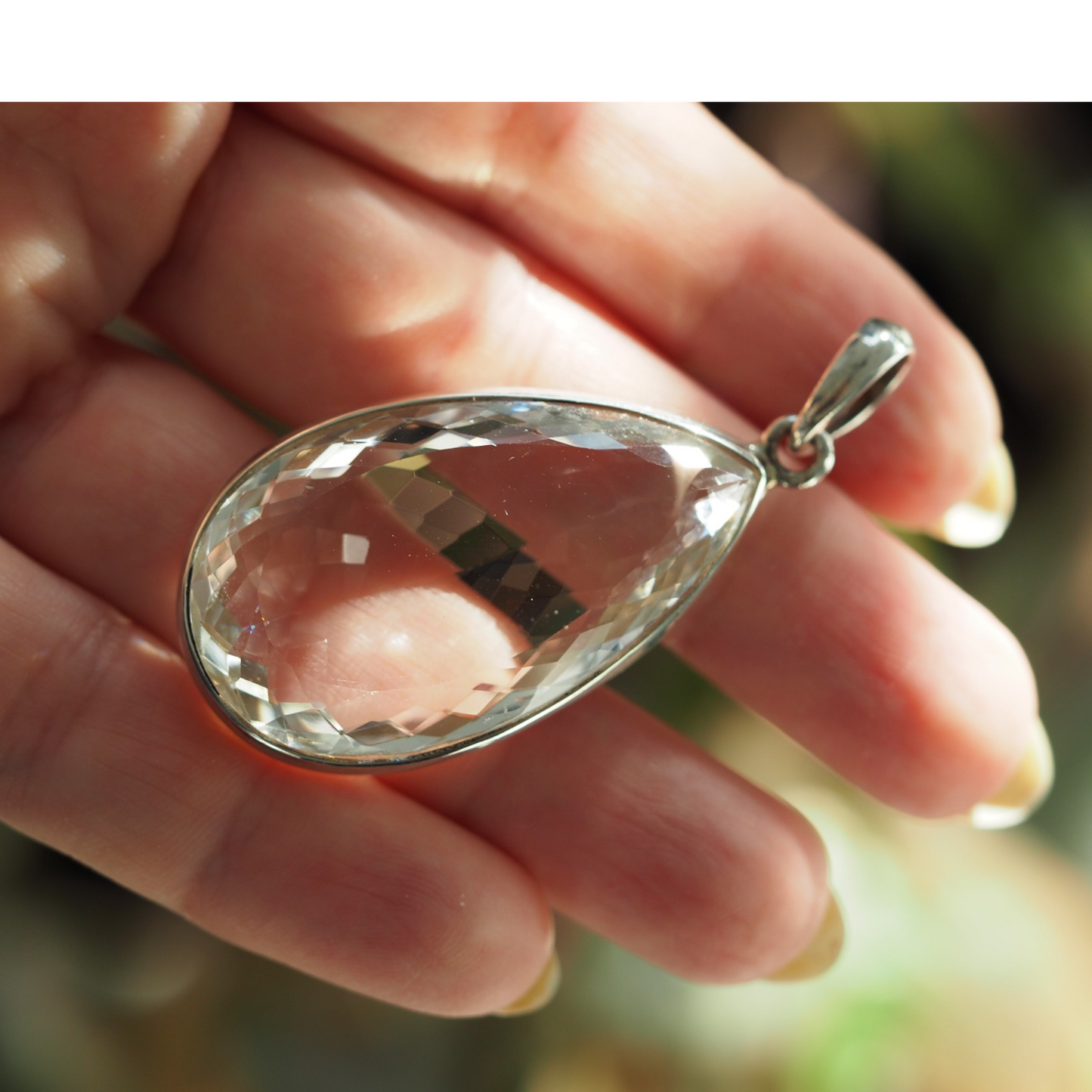 Scale view of large clear teardrop pendant in hand