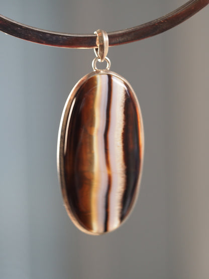 Large 2000s silver banded agate pendant shown on a collar, with bold brown, black, white, and translucent vertical bands