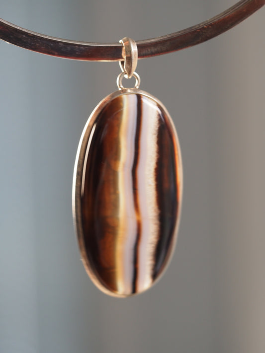 Large 2000s silver banded agate pendant shown on a collar, with bold brown, black, white, and translucent vertical bands