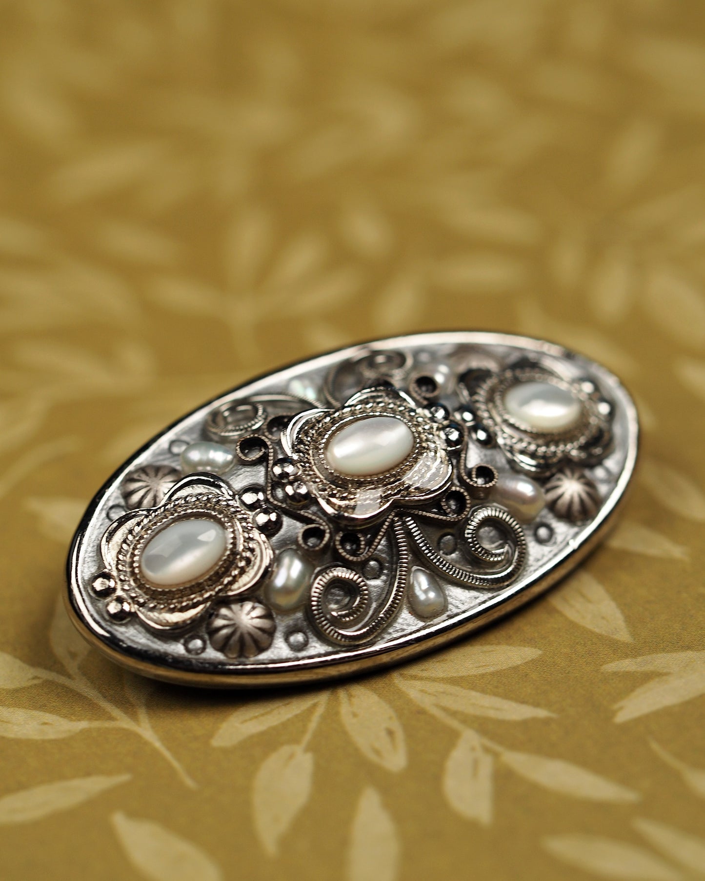Close-up of three glass cat's-eye cabochons with rope-twist bezels and ornate scrollwork