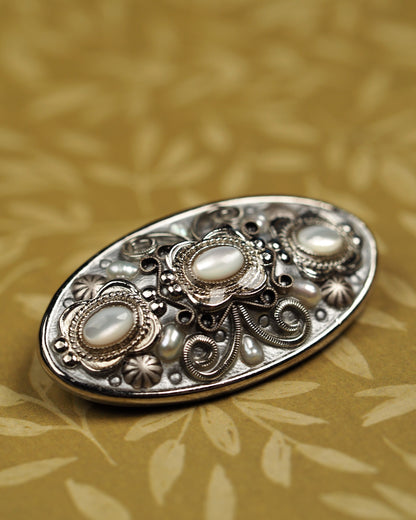 Close-up of three glass cat's-eye cabochons with rope-twist bezels and ornate scrollwork