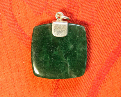 aventurine pendant flat on orange linen, back view showing the smooth polished reverse and silver cap