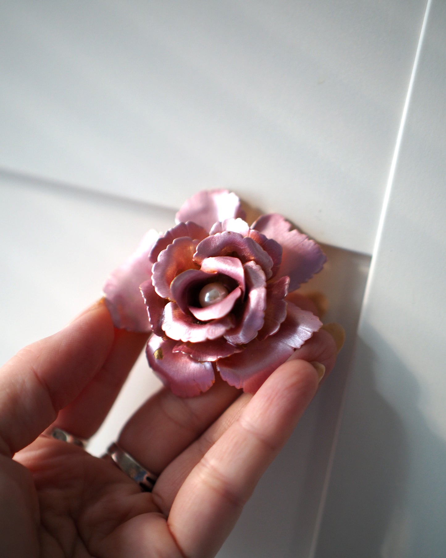 Pink enamel rose brooch held in hand to show 2.25-inch scale and dimensional height