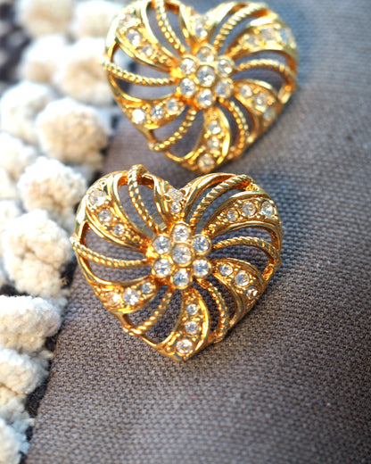 close-up of the pinwheel motif showing alternating smooth and rope-textured gold-tone petals with pavé-set clear rhinestones