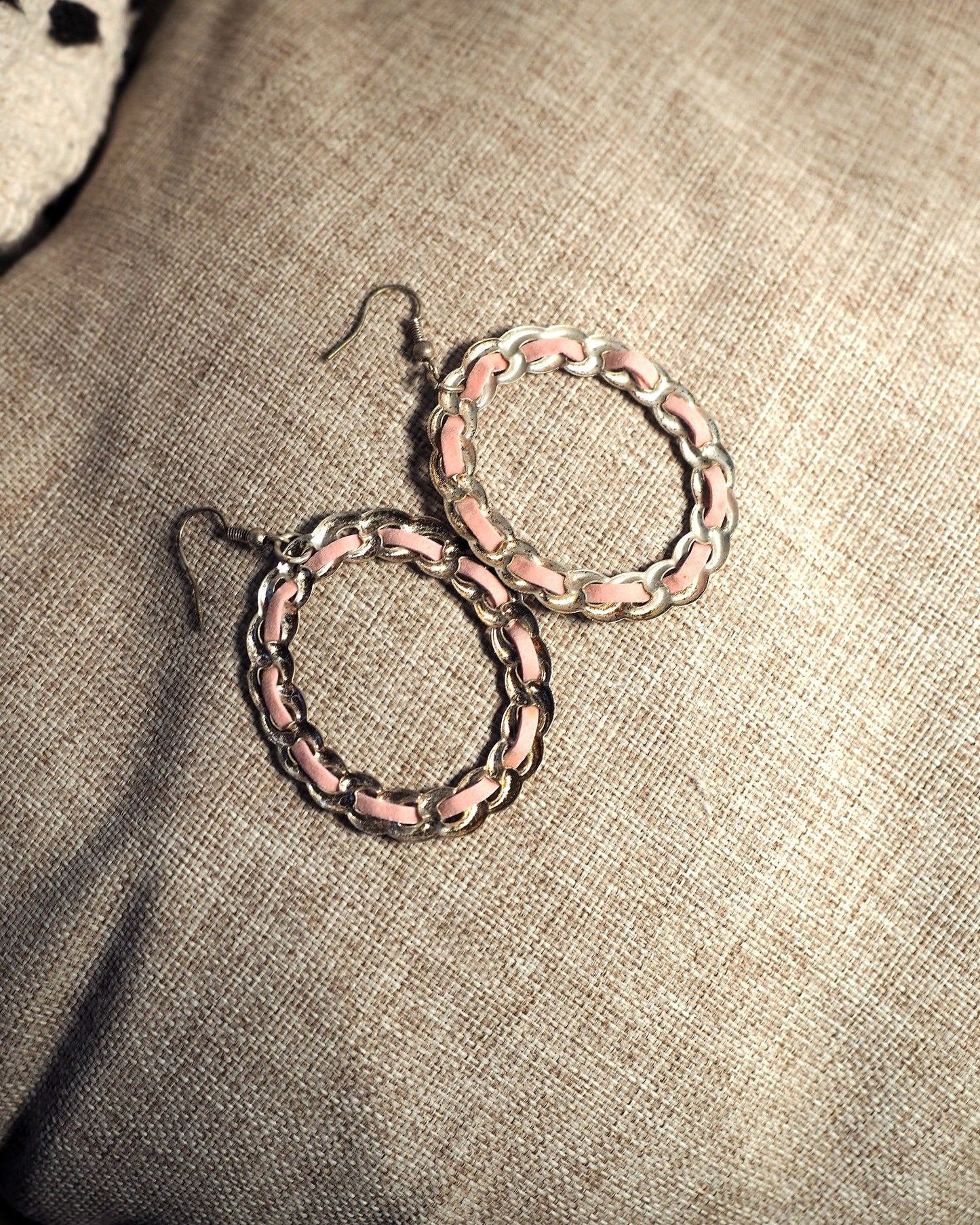 Close-up of 1970s pink enamel and silver-tone chainlink hoop earrings showing alternating enamel bars and curved metal links