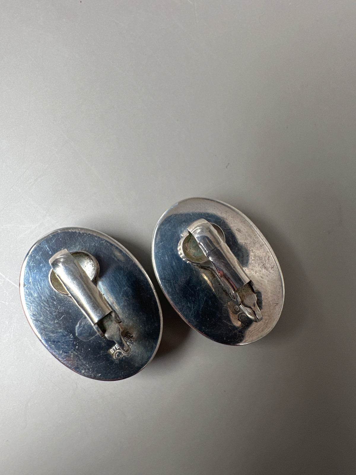 Reverse view of both earrings showing clip mechanisms and construction