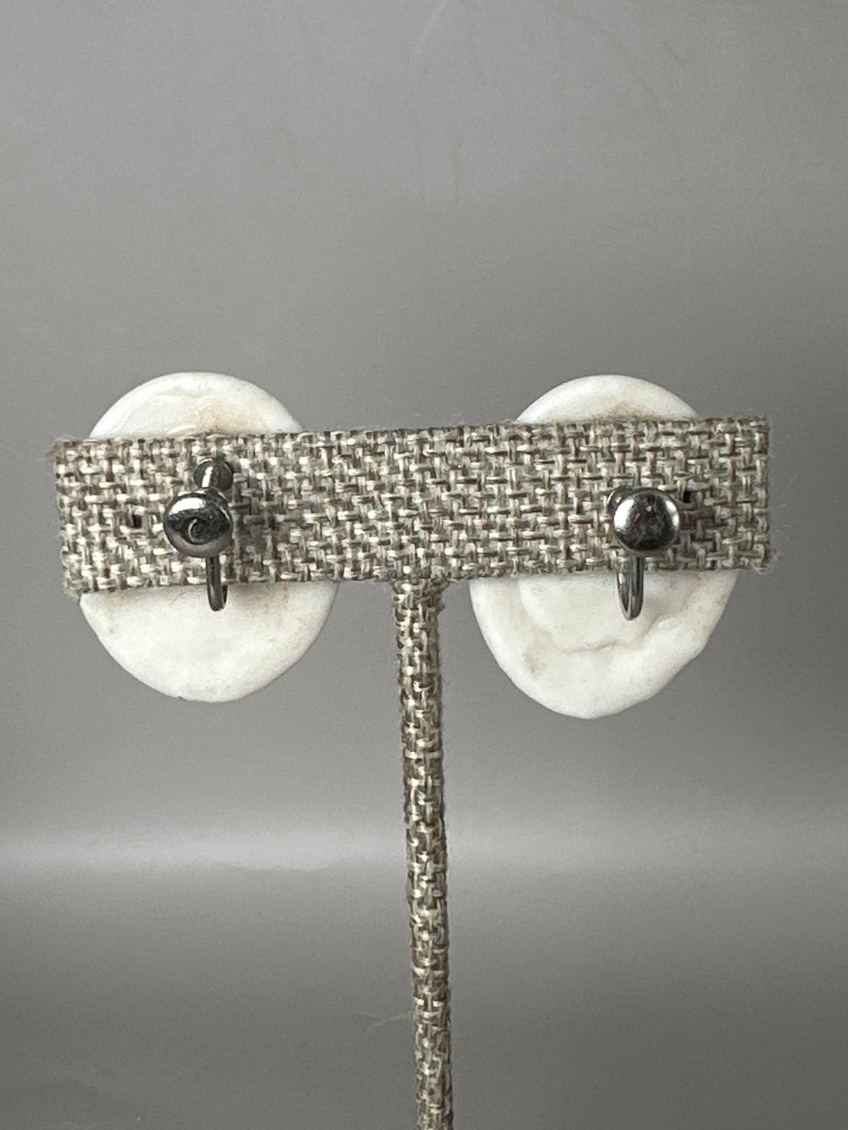 Back view of white ceramic earrings showing silver-tone screw-back mechanisms