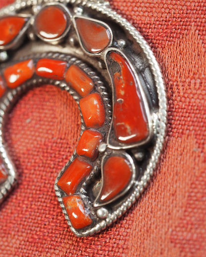 Detail of coral-inlaid naja arc with teardrop and crescent bezels, visible twisted rope frames