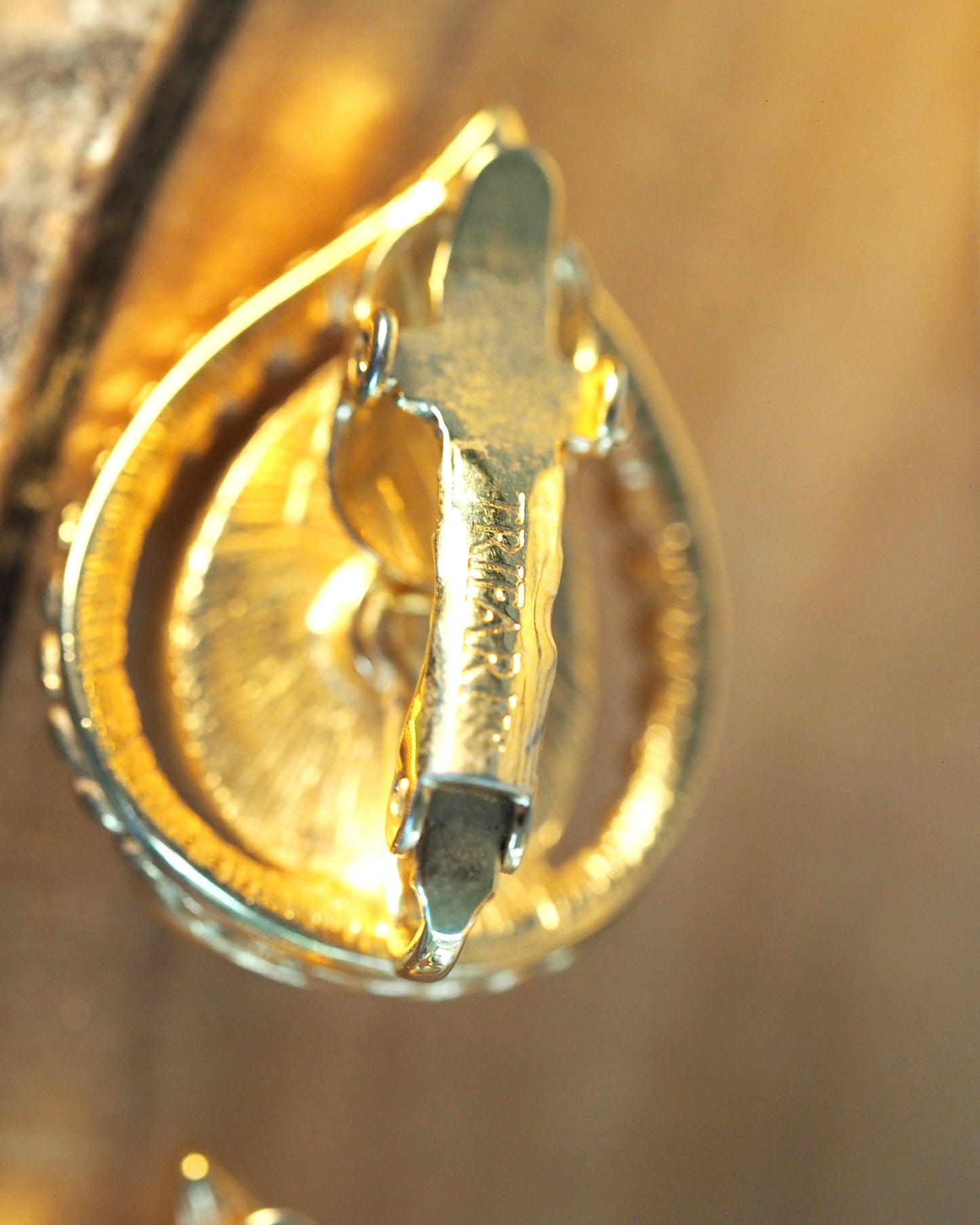 Close-up of Trifari signature stamp on the clip-on mechanism bar, reading 'Trifari' in raised letters