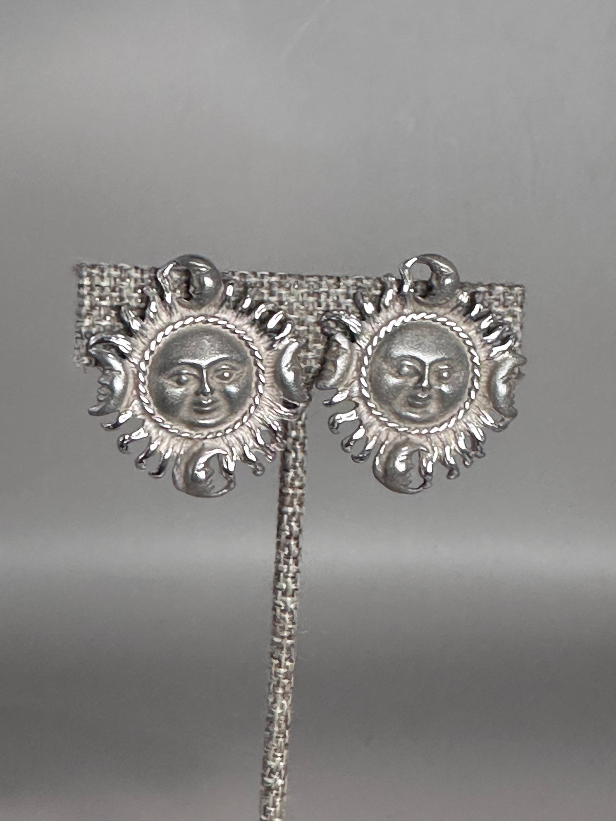 Sterling silver Taxco sun and moon clip earrings shown from the front, each featuring a sun face surrounded by radiating rays with four crescent moons