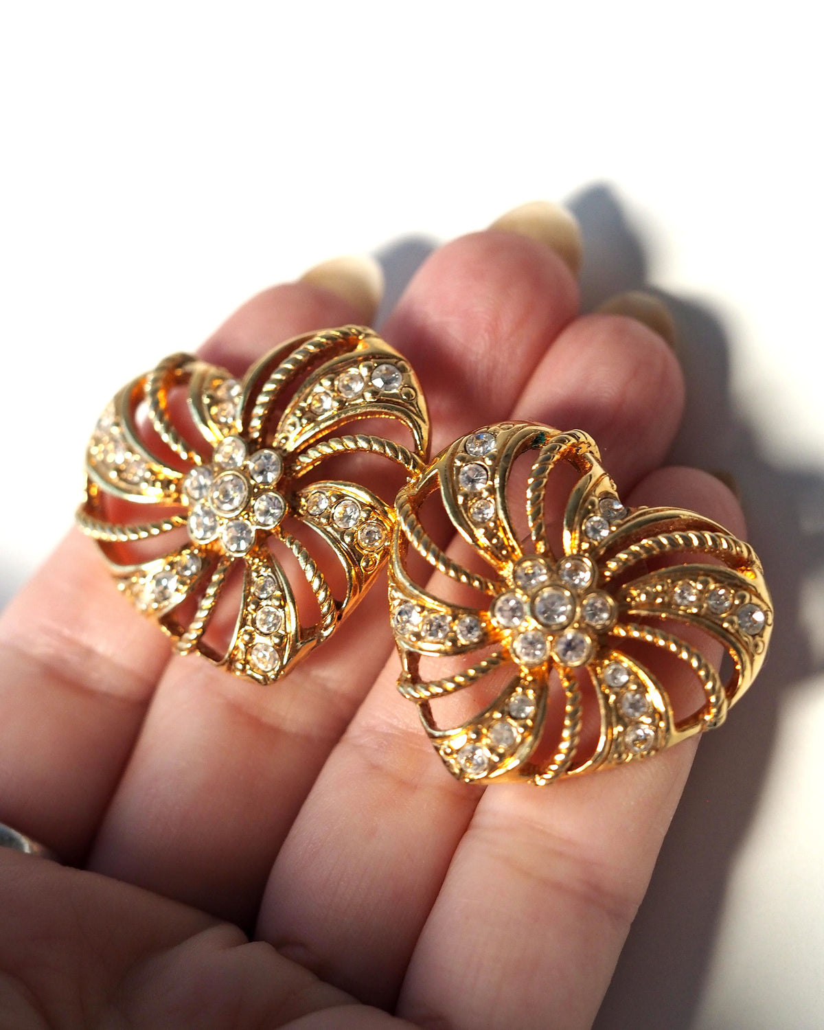 pair of earrings held in hand for scale, showing the 1.25-inch height against fingertips