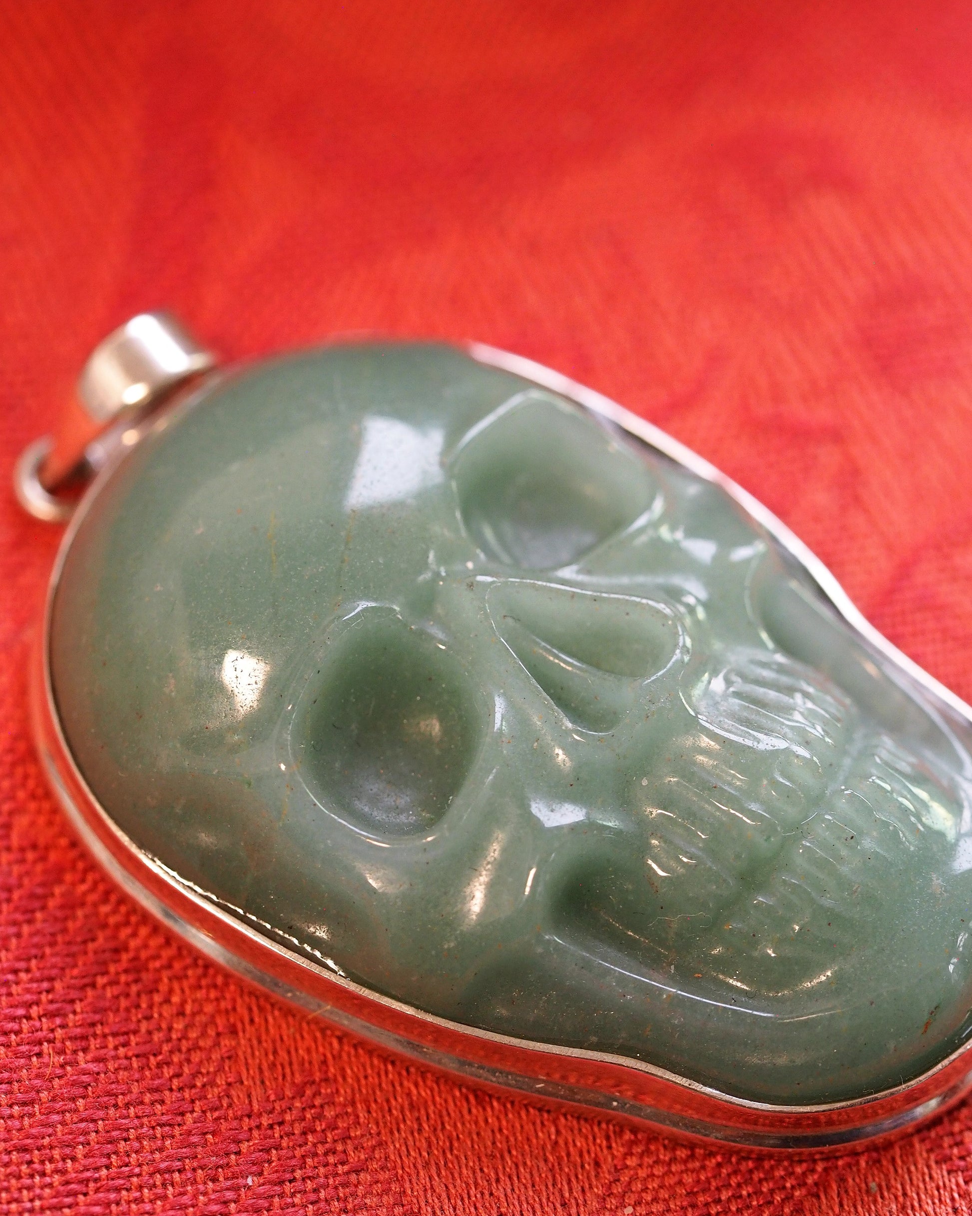 Close-up of aventurine skull carving showing eye socket depth, nasal cavity detail, and translucent green stone with internal sparkle