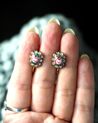 Painted rose screwback earrings shown on fingertips for scale, approximately three-quarters inch long
