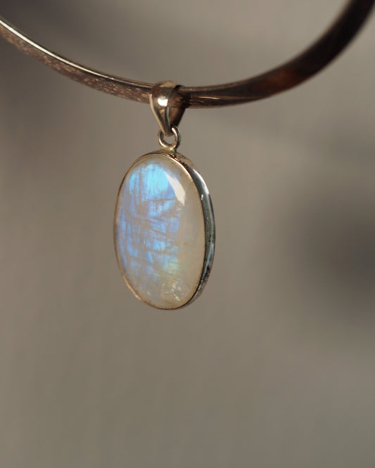 Sterling silver rainbow moonstone pendant on chain, front view showing blue adularescence in oval cabochon
