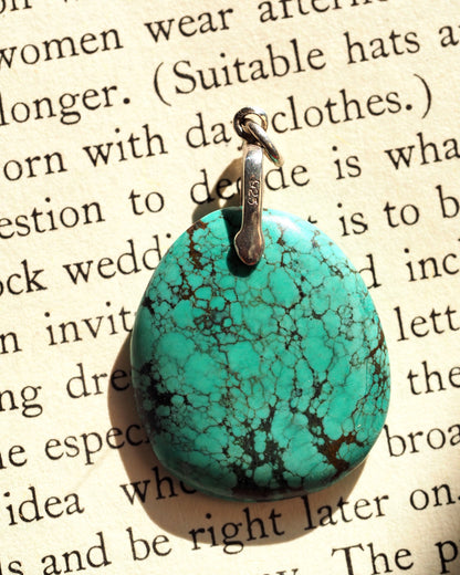 Side view of blue-green stone pendant showing 925 stamp on sterling silver bail and domed profile