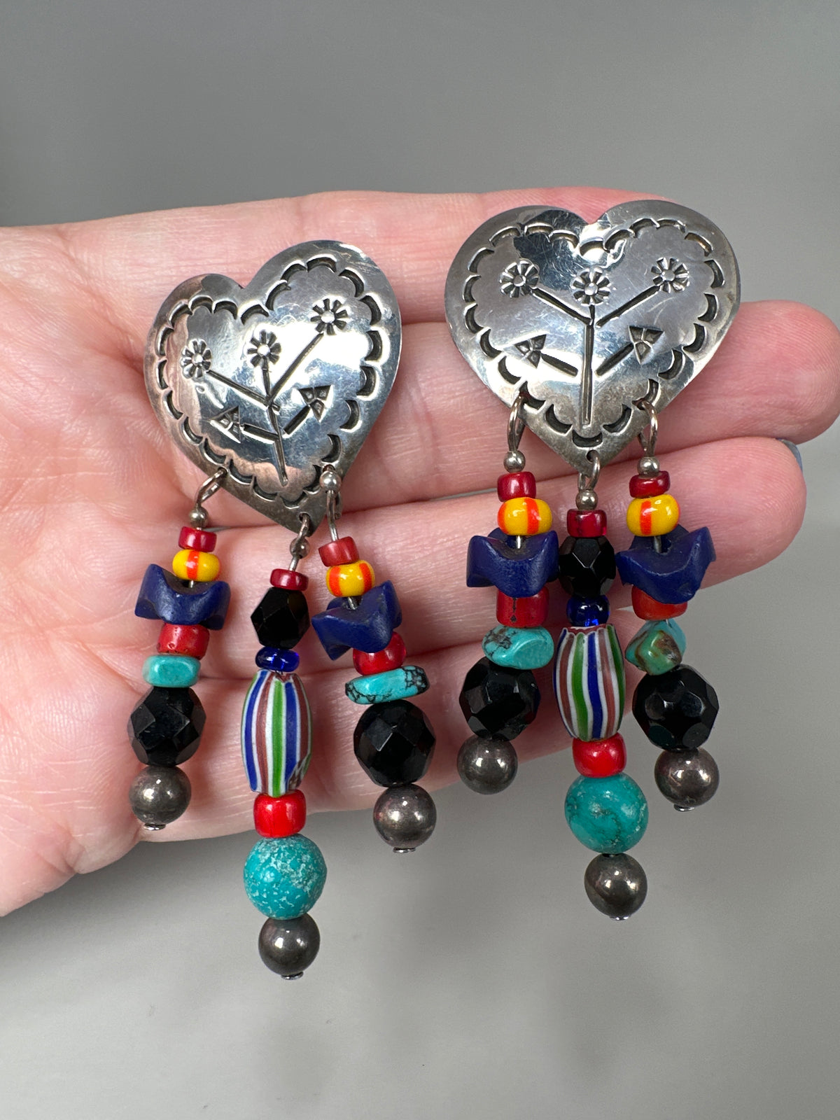 Taxco heart earrings held in hand for scale, showing 2.75-inch length with turquoise, black, and chevron glass beads