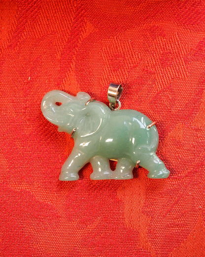 Aventurine elephant pendant on red fabric, side view showing three-dimensional carved silhouette and sterling silver bail
