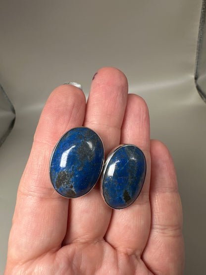 Hand-held scale view of both earrings showing 1-inch size