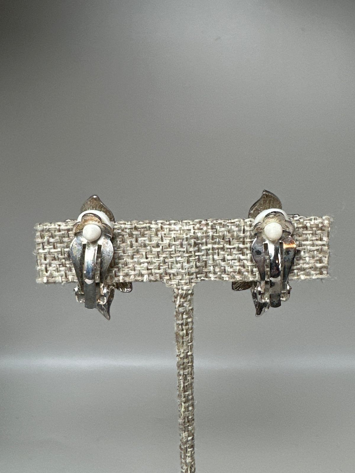 Rear view of clip-on earrings showing hinged paddle-style backs with white comfort pads
