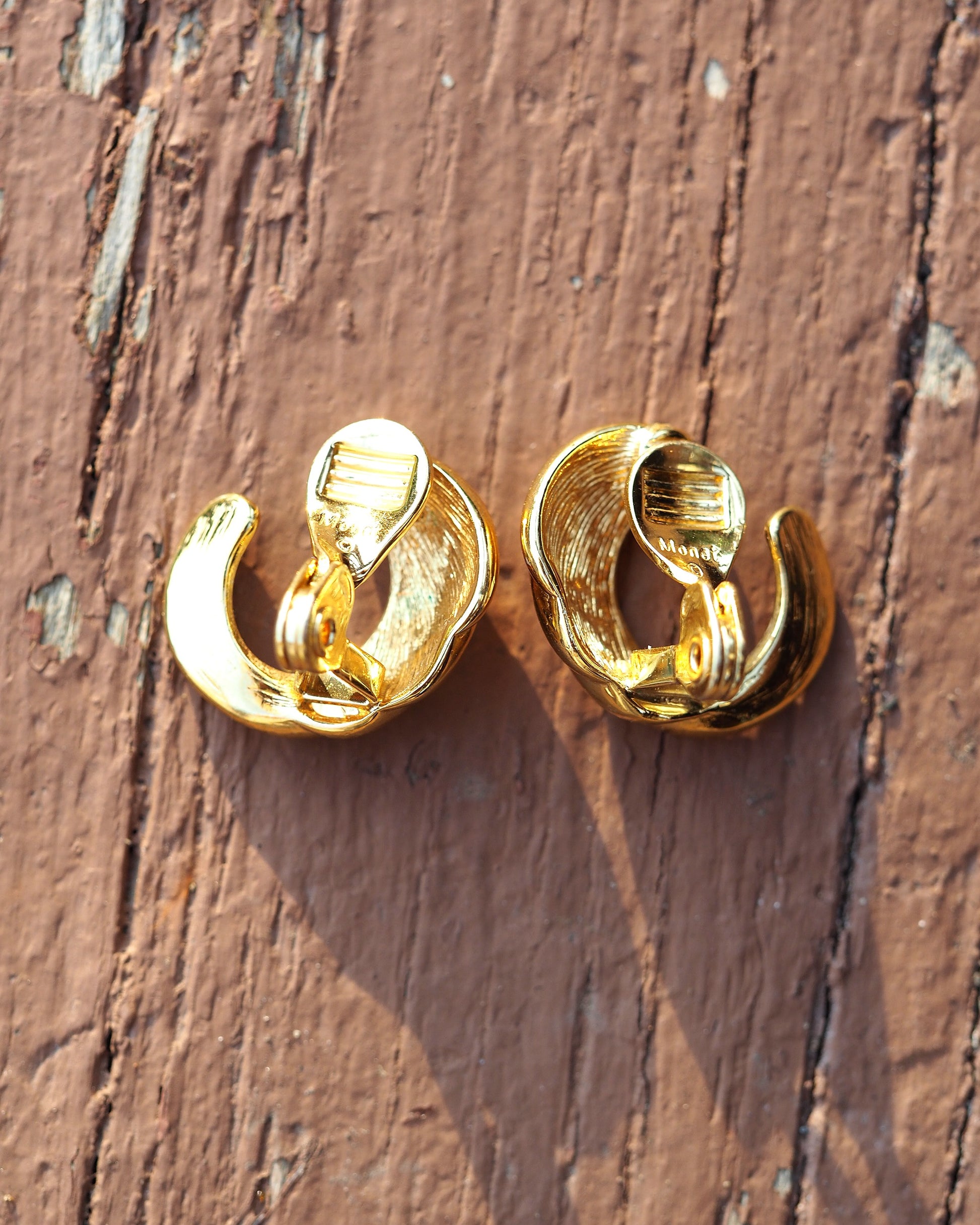 Reverse view of Monet clip earrings showing clip-on backs with ribbed comfort pads and signature stamp