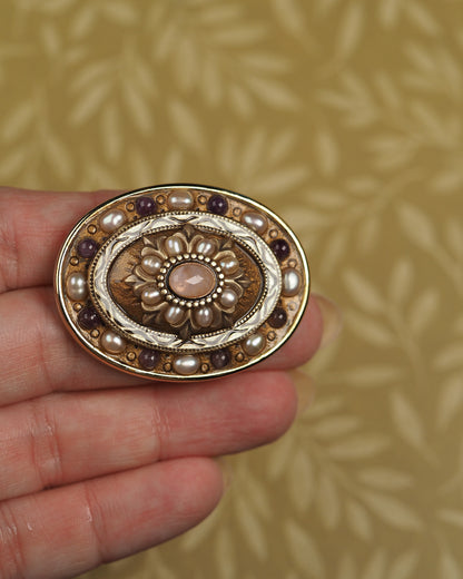 Signed Michal Golan brooch held on fingertips for scale, showing 1.75-inch oval size