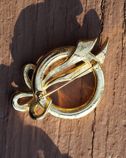 Reverse of the Nolan Miller brooch showing radial brushed texture, rollover pin clasp, and signature on the pin stem
