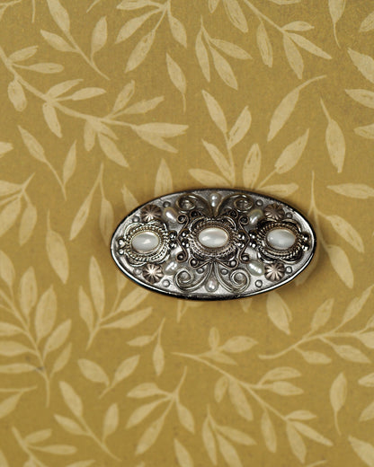 Signed Michal Golan silver-tone filigree brooch with three pale cat's-eye cabochons, front view