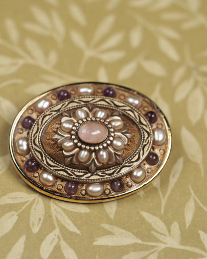 Detail of concentric rings with pearl-like beads, engraved leaves, and purple cabochons on Michal Golan brooch