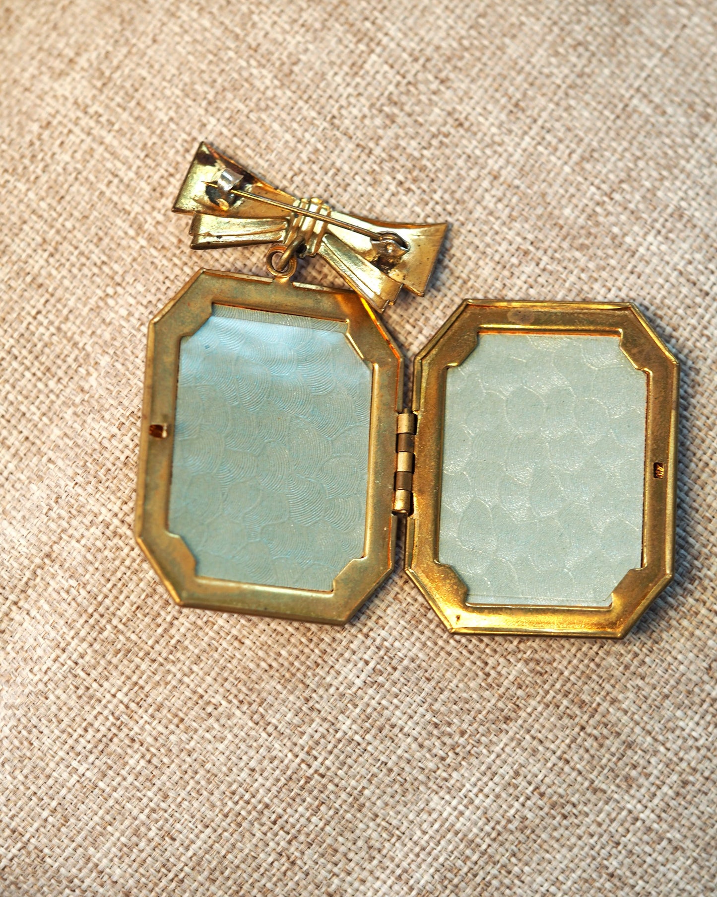 Locket brooch opened to reveal two rectangular picture frames under clear plastic