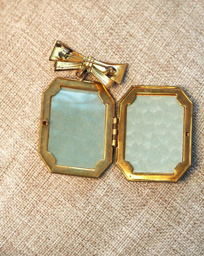 Locket brooch opened to reveal two rectangular picture frames under clear plastic