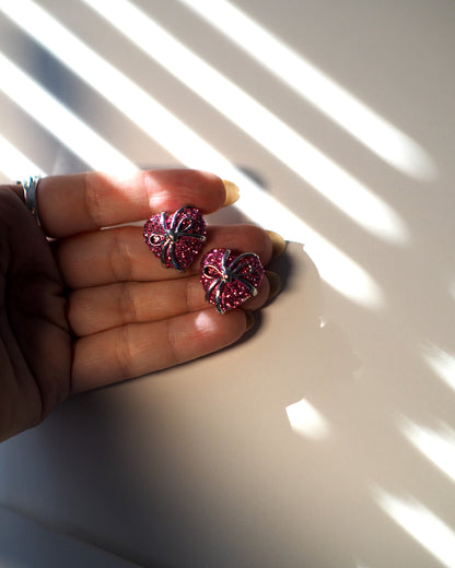 1980s pink rhinestone heart earrings shown in hand for scale, three-quarter-inch size