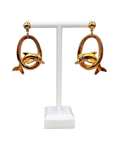 Front view of pair of Avon dolphin dangle earrings on white T-bar stand showing full drop and rhinestone eyes