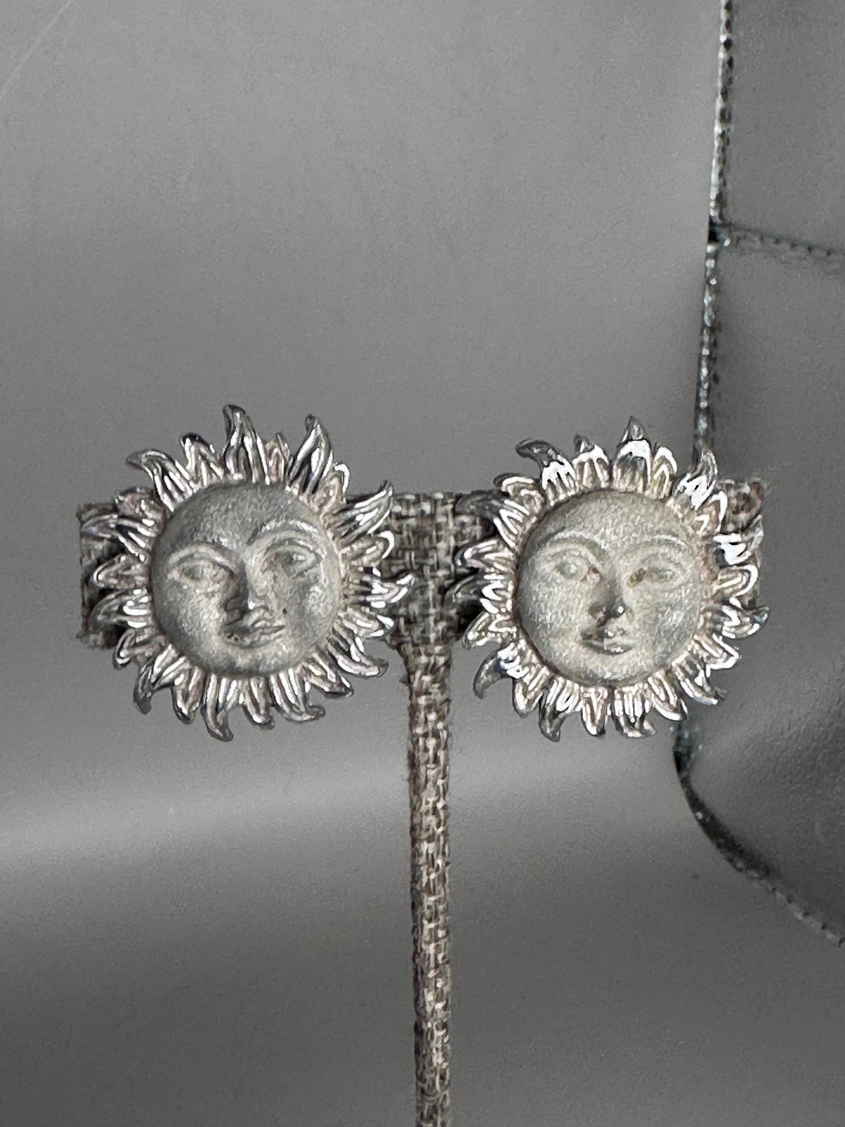 Sterling silver Taxco sun face clip earrings with radiating flame rays, front view showing detailed facial features and polished ray tips