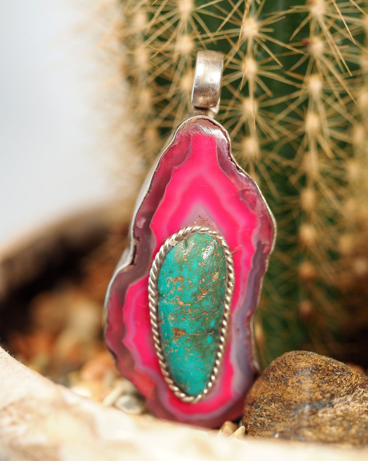 Dyed pink agate slice pendant with oval blue-green cabochon, front view