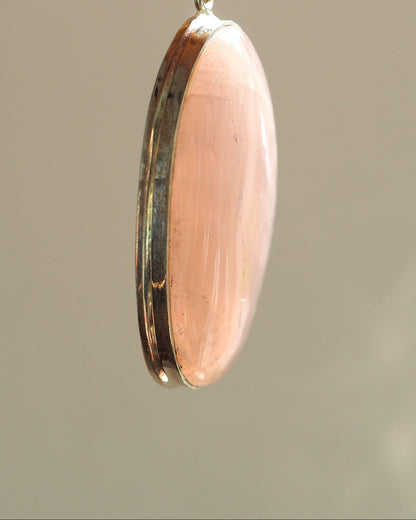 Side profile of rose quartz pendant showing domed stone height above bezel and light bezel wear