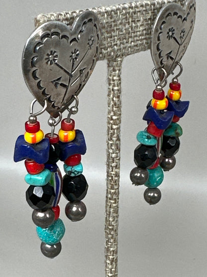 Side angle of Taxco heart earrings showing stamped floral cutwork and beaded strands with turquoise and chevron beads