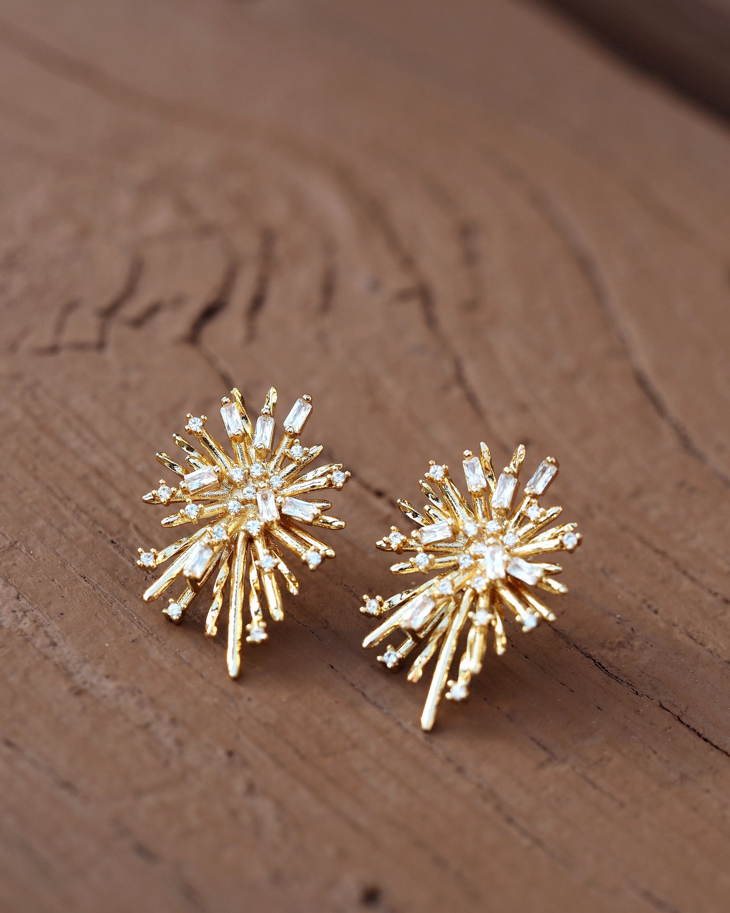 Pair of 1960s starburst earrings, angled view showing dimensional layered rays and rhinestone prong settings