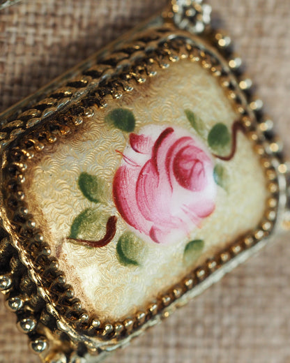 Close-up of one earring showing the hand-painted pink rose on cream-and-gold guilloché background with beaded trim detail