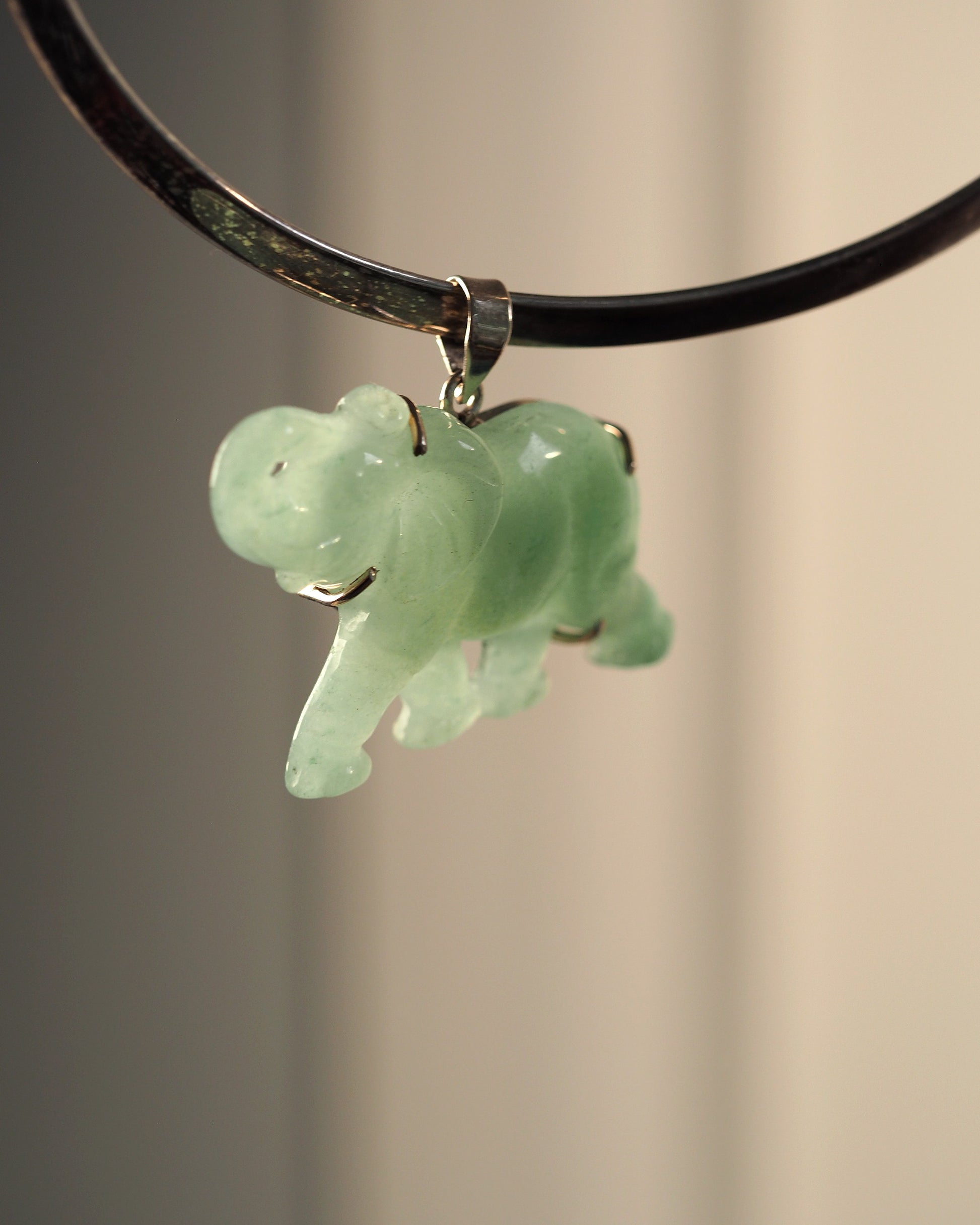 Sterling silver aventurine elephant pendant hanging from black cord, front view showing raised trunk and pale green translucent stone