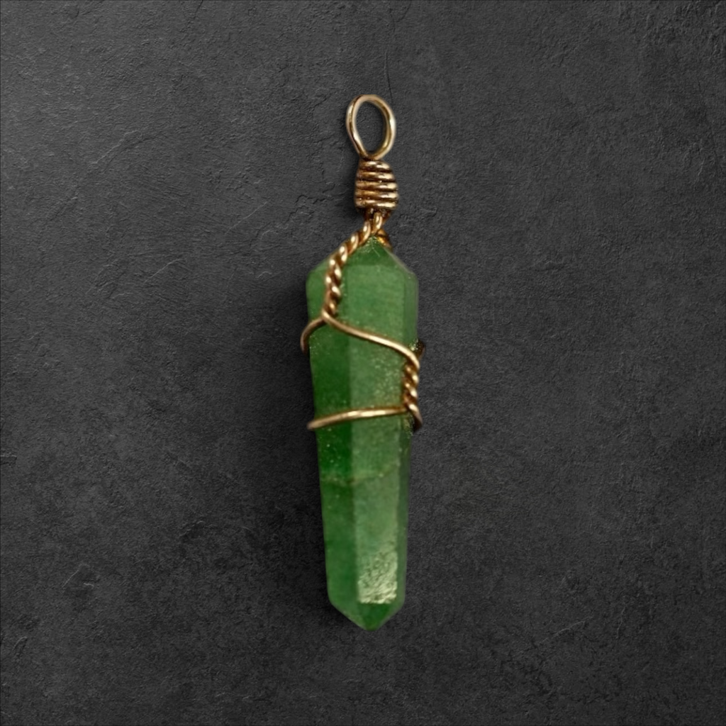 GlamGram NYC green aventurine crystal point pendant with gold-toned wire wrap on a dark textured background.