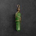 GlamGram NYC green aventurine crystal point pendant with gold-toned wire wrap on a dark textured background.