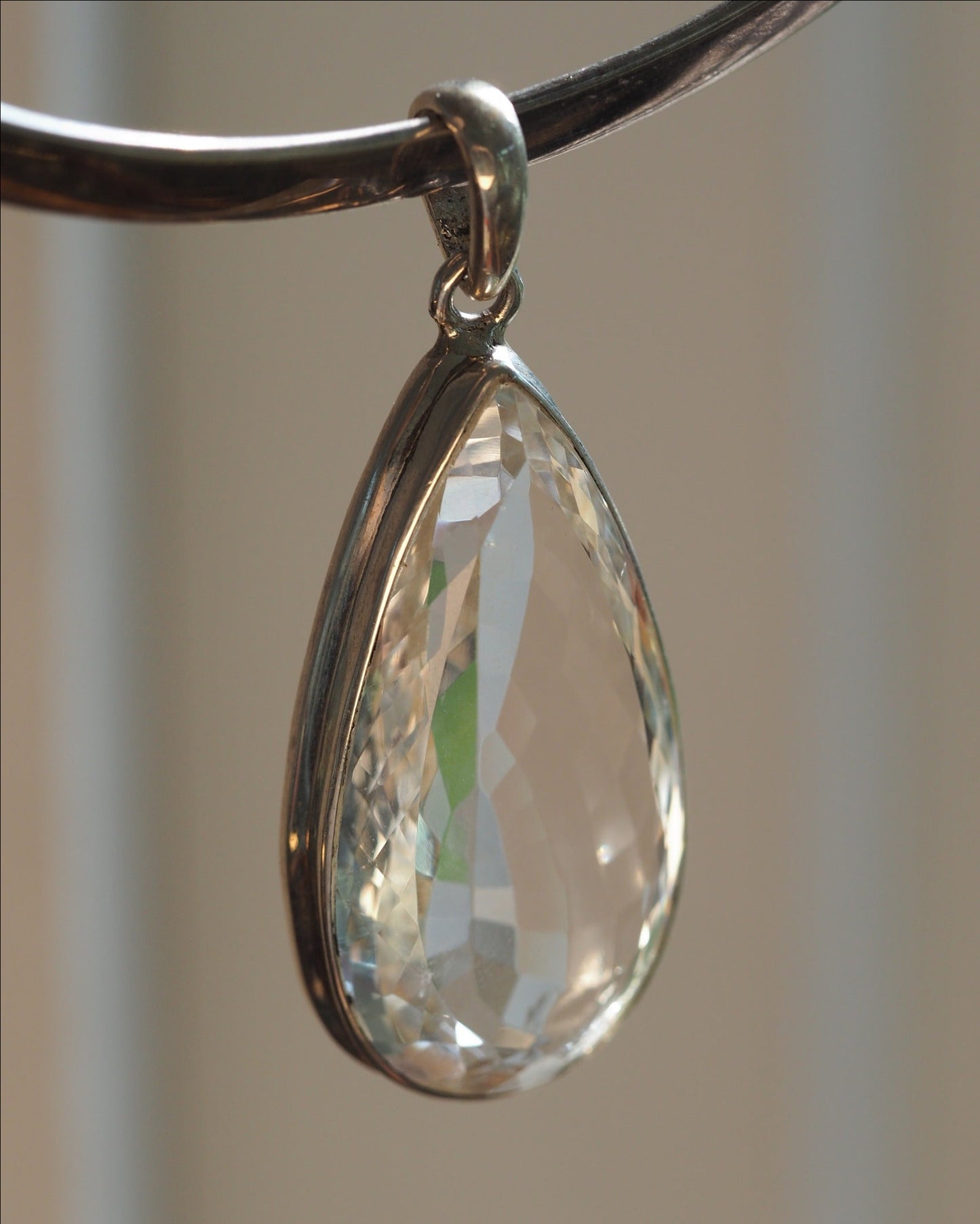 Faceted clear stone teardrop pendant in sterling silver bezel, front view showing rows of light-catching cuts