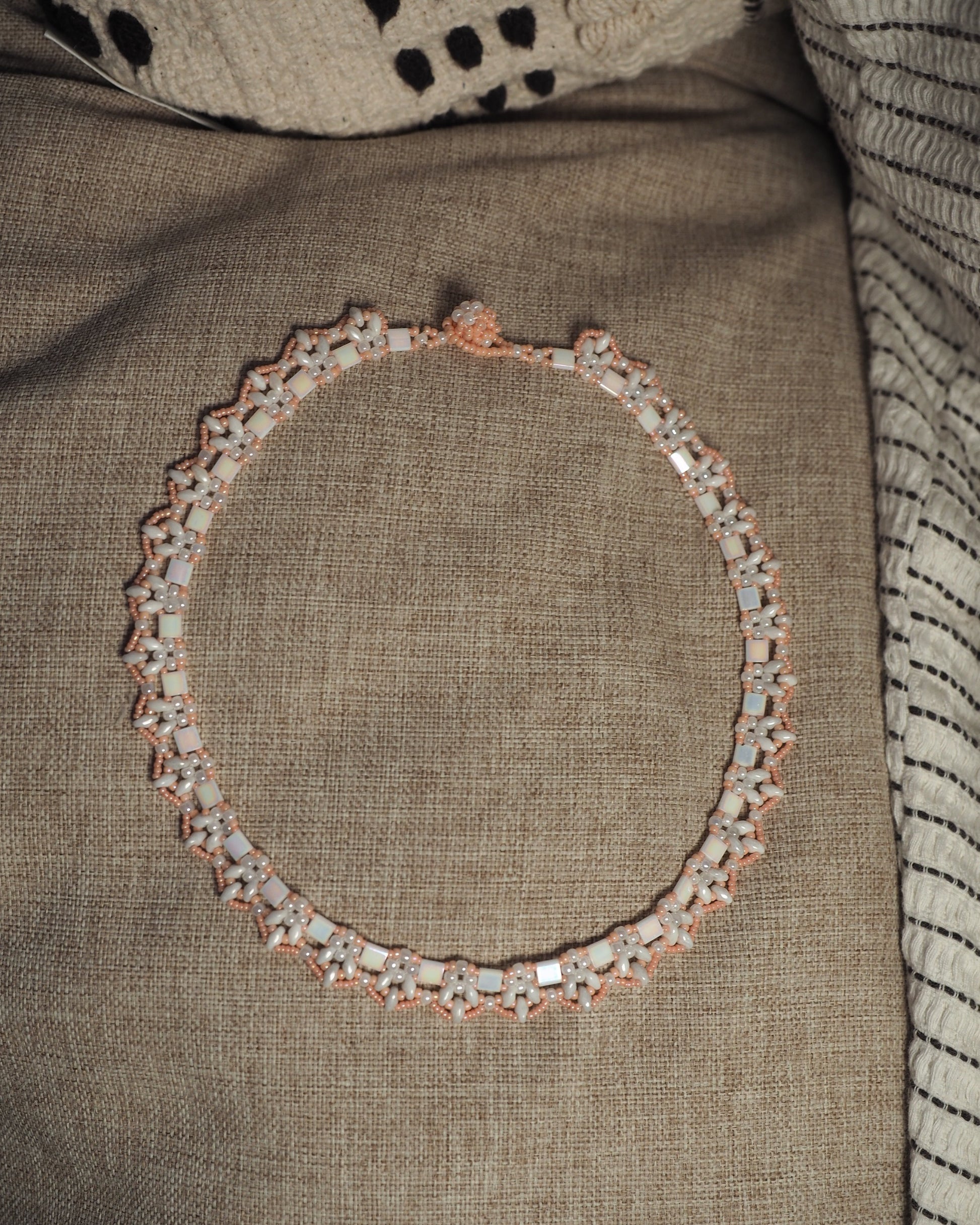 Full view of handmade beaded collar necklace on neutral linen, 17 inches around with button closure at top