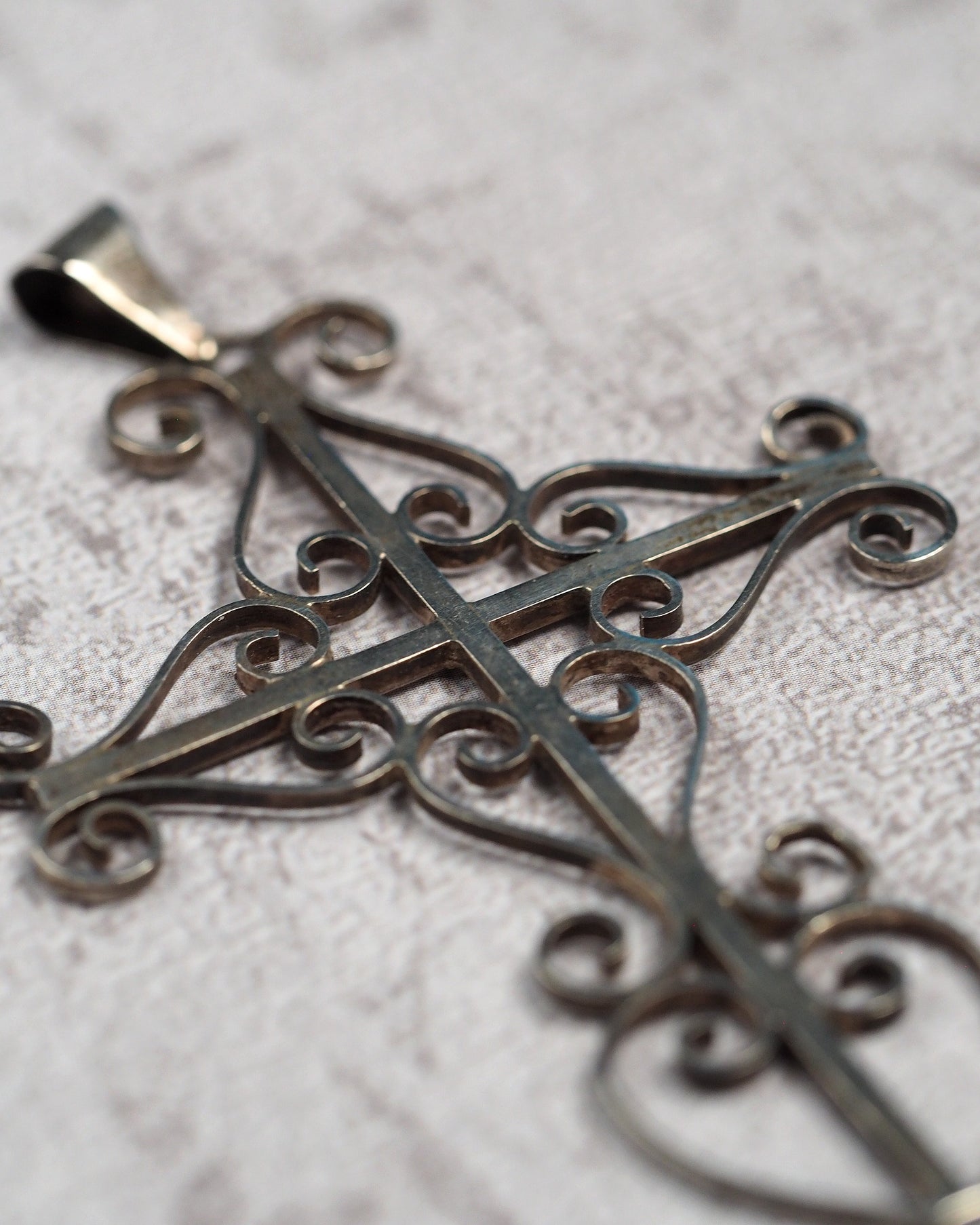 Three-quarter view showing the dimensional openwork cross and slide bail