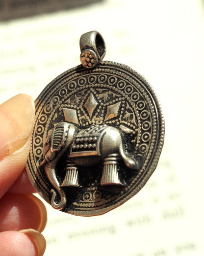 Side angle of sterling elephant medallion showing depth of relief and decorative bail